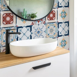 Mediterranean mosaic tiles behind a modern white oval countertop washbasin
