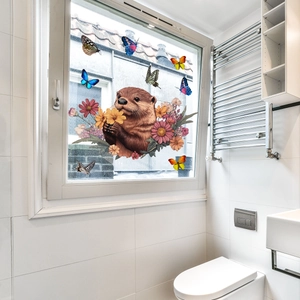 Détail de stickers de fenêtre loutre et fleurs sur une surface vitrée de salle de bain
