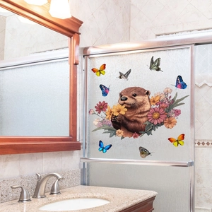 Détail d'autocollants loutre et fleurs sur une porte de douche en verre dépoli
