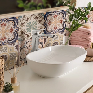 Detail of Mediterranean tile stickers on bathroom wall behind white ceramic washbasin
