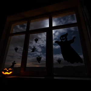 Detailopname van zwarte spooksilhouetten en pompoen op een raam in de nacht