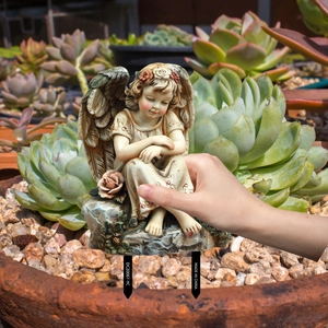 Garden stake with angel figurine sitting in a flower pot among succulent plants