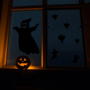 Detail van zwarte spook-raamstickers met pompoenlantaarns op de vensterbank in de nacht