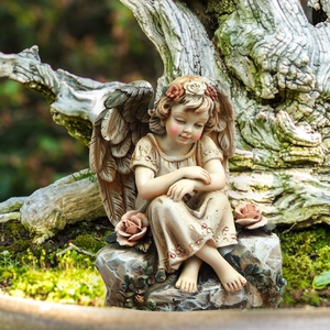 Detailed garden angel statue with resin wings and rose accents on a mossy root