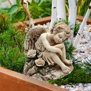 Sleeping angel garden stake figurine with resin wings and rose details on pine needles
