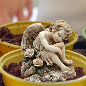Close-up of a sleeping angel garden statue with detailed wings and rose base decor