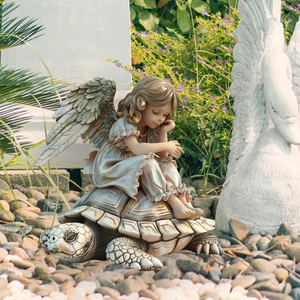 Detailed garden statue featuring a small fairy with wings sitting on a large sea turtle