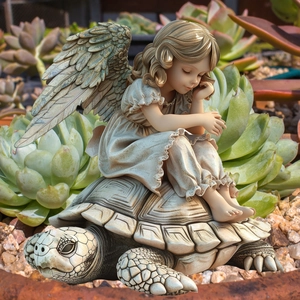 Garden angel statue sitting on a turtle figurine amidst lush green succulent plants