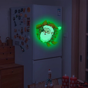 Luminous Santa Claus fridge magnet with green wreath glowing in a dark room setting