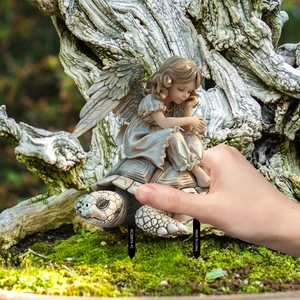 Macro view of winged fairy sitting on a turtle garden stake with soil plug details