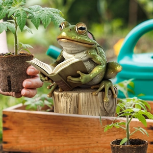 Detail of frog reading a book on a stump decorative garden stake made of resin