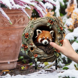Realistic red panda garden stake with floral tree ring decoration in a snowy garden