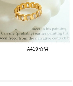 Close-up of gold chain ring with rectangular zircons on a white ceramic plate