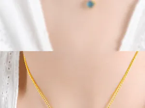 Detail of elegant gold-tone cube pendant necklace on neck showing fine chain texture