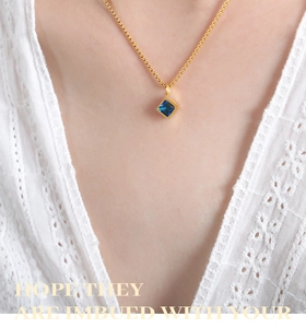 Detail of square blue zircon pendant on a gold titanium steel chain necklace