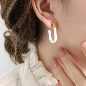 U-shaped gold and white enamel earrings with 18K plating shown on model's ear