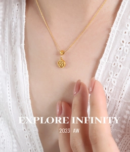 Close-up of golden hollowed-out double happiness character pendant on a dainty chain