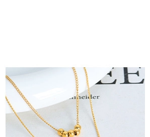 Detailed macro view of a gold-plated titanium steel necklace with small golden beads