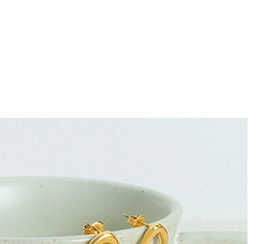 Close-up of golden U-shaped hook earrings on ceramic cup showcasing modern minimalist style