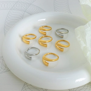 Set de anillos geométricos abiertos en acabados oro y plata pulidos sobre bandeja