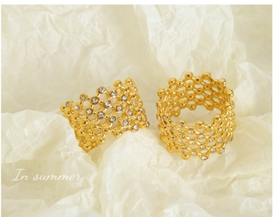 Macro shot of 18k gold mesh hollow rings with sparkling zircons on textured background