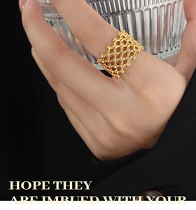 Detail of gold geometric honeycomb hollow ring with zircon stones worn by a model