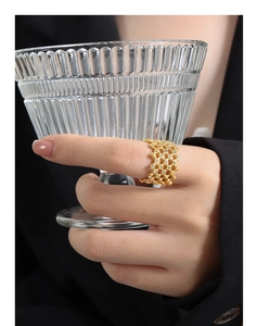 Detail of gold hollow grid ring with micro-pave crystals on model holding a glass