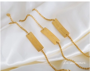 Close-up of three gold titanium bracelets with engraved Happy Forever rectangular plates