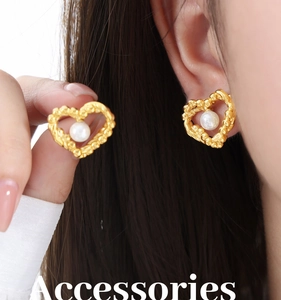 Macro view of gold heart earrings with pearl inlay worn on ear for detail