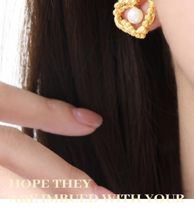 Detail shot of heart-shaped gold earring featuring a pearl inlay on a female model
