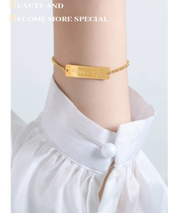 Detailed view of gold plated bracelet featuring a polished plate engraved with Happy Forever