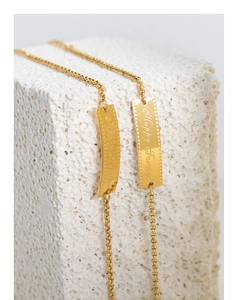 Detail of gold titanium steel bracelet featuring engraved Happy Forever square pendant