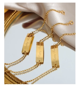 Detail of 18k gold plated curved rectangular bar bracelet with Happy Forever engraving