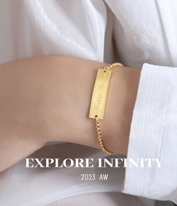 Macro shot of gold titanium steel bracelet with rectangular Happy Forever engraved charm