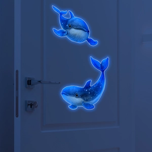 Glow-in-the-dark blue whale wall stickers on a door showing luminescent night effect