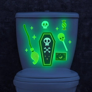Luminous Halloween stickers with glowing skulls and ghosts on a white toilet surface