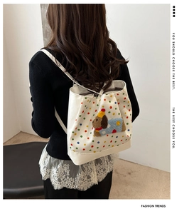 Close-up of stylish white tote bag featuring colorful polka dots and a 3D plush puppy patch