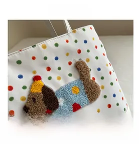 Detail of 3D textured puppy embroidery on a white polka dot tote bag with vibrant colors