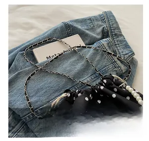 Detailed view of polka dot bucket bag with pearl handle and metal butterfly charm