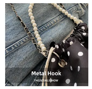 Close-up of detachable silver metal hook and pearl handle on black polka dot bucket bag