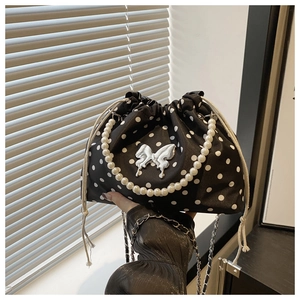 Detailed view of polka dot bucket bag with pearl handle and metal bow decoration