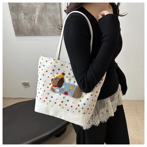 Detailed close-up of a white polka dot tote bag with a cute 3D plush puppy patch