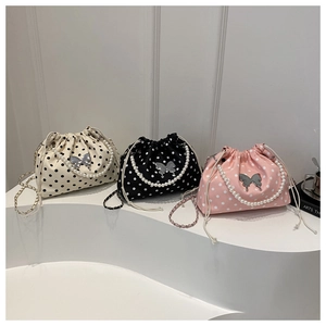 Detailed view of three polka dot bucket bags in cream, black, and pink with pearl handles