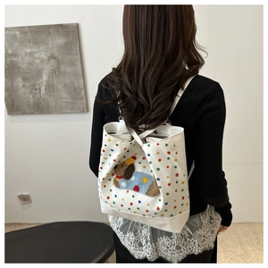 Detailed plush puppy embroidery and colorful polka dots on a white canvas backpack