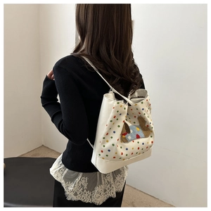 Rear view of white canvas backpack with colorful dots and plush animal embroidery on model