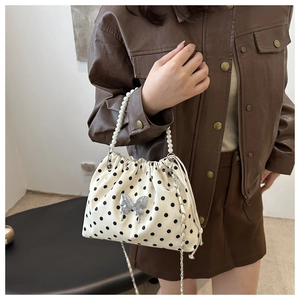 Close-up of polka dot bucket bag with pearl handle and silver butterfly charm detail