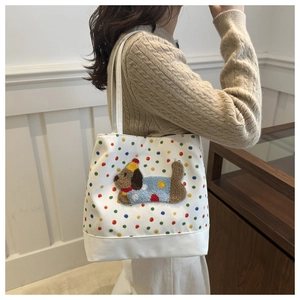 Detail of white canvas tote bag with colorful polka dots and brown plush puppy embroidery