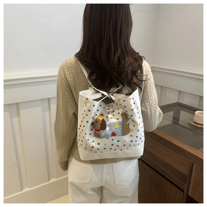 Detail of white tote bag featuring colorful polka dots and a plush puppy embroidery