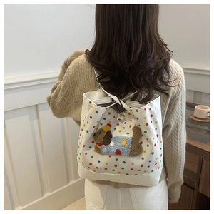 Detailed view of white polka dot drawstring bag with a 3D plush puppy patch on model