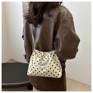 Detail of polka dot bucket bag featuring pearl handle and metallic butterfly buckle